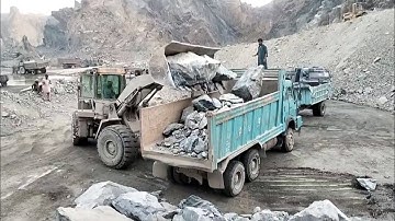 Heavy machine rocks loading in action: caterpillar loader 966D big rocks loading damper and trolleys