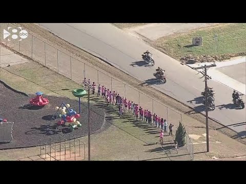 Athena Strand's classmates, dressed in pink, wave to motorcycles in her honor