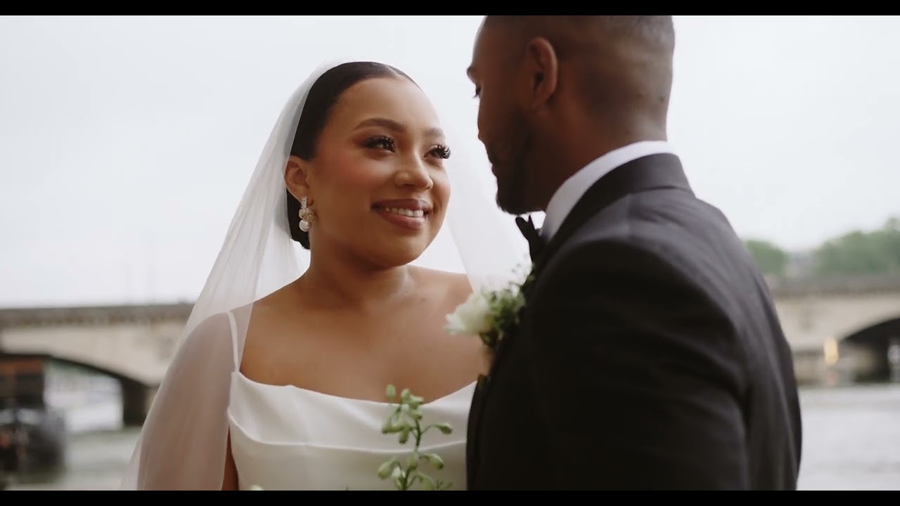 Bride and groom smile by the Seine under a bridge, her veil glowing softly