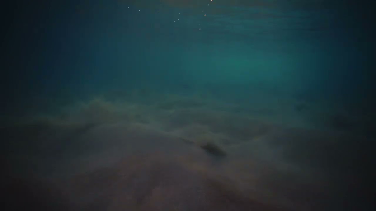 underwater view of mystic turquoise green rays of light on sandy water
