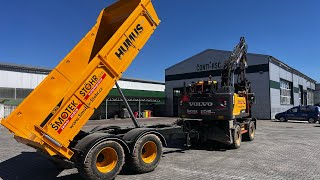 Excavator with siding during preparation under the panel area and stacking the panels