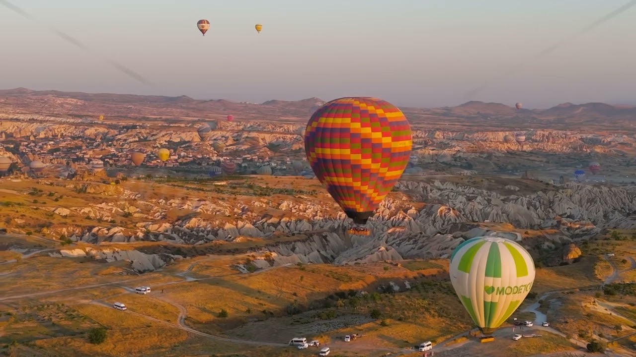 Goreme, Nevsehir, Turkey. Large checkered hot air balloon launching and rising at dawn over Cappa...