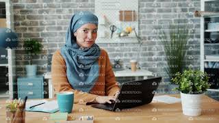 Attractive woman in hijab working in office with laptop then looking at camera screenshot 4