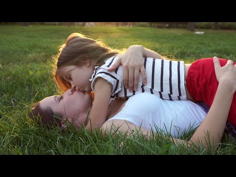 Mother and daughter lying on grass. Kiss