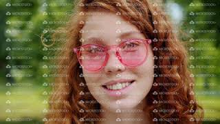 Close-up of pretty redhead girl with freckles wearing sunglasses in park