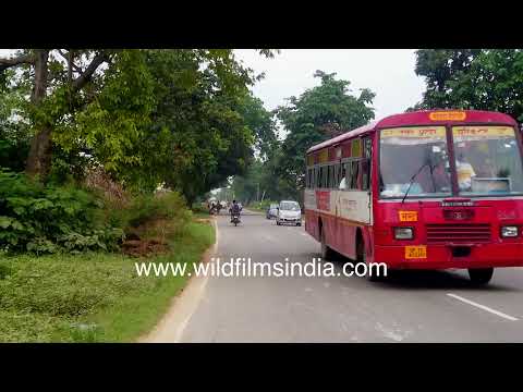 Red bus and motorcycle traffic on a rural road near Ganeshpur