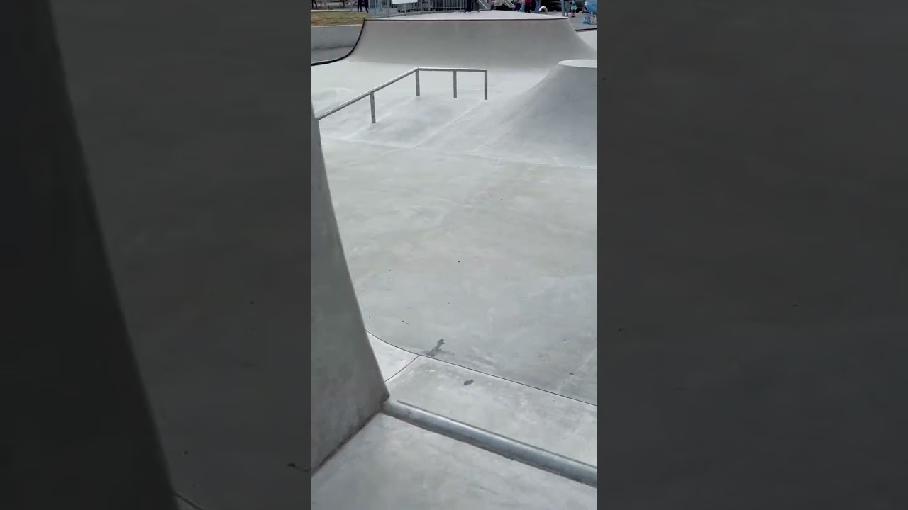 Skateboarder rides around kid on scooter in orange helmet at skatepark and knocks her down