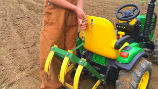 Farm Kid Driving Modified John Deere Toy Tractor With Cultivating Tines In The Garden