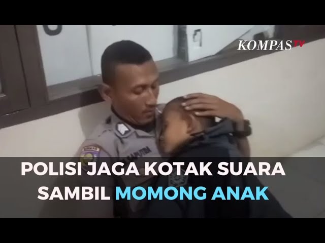 Polisi Jaga Kotak Suara Sambil Momong Anak class=