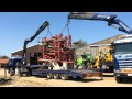 2 Truck cranes putting a huge cultivator on 1 lorry