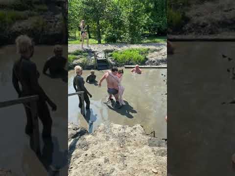 Man helps a disabled woman into a mud bath.