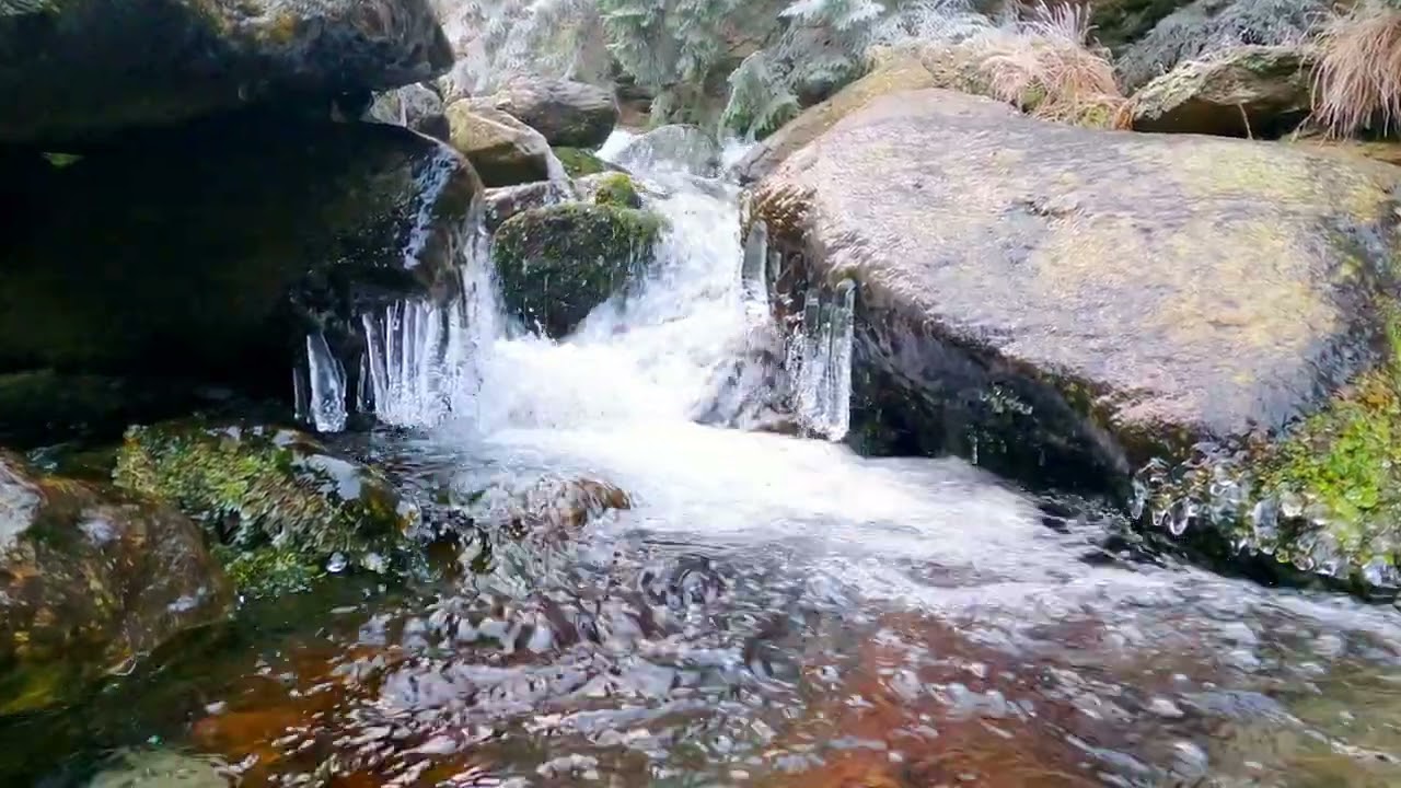 water fall among frozen rocks, mountain river in winter - zoom in