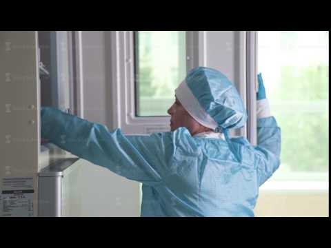 Woman lab assistant in blue sterile clothes - hat and gloves - works