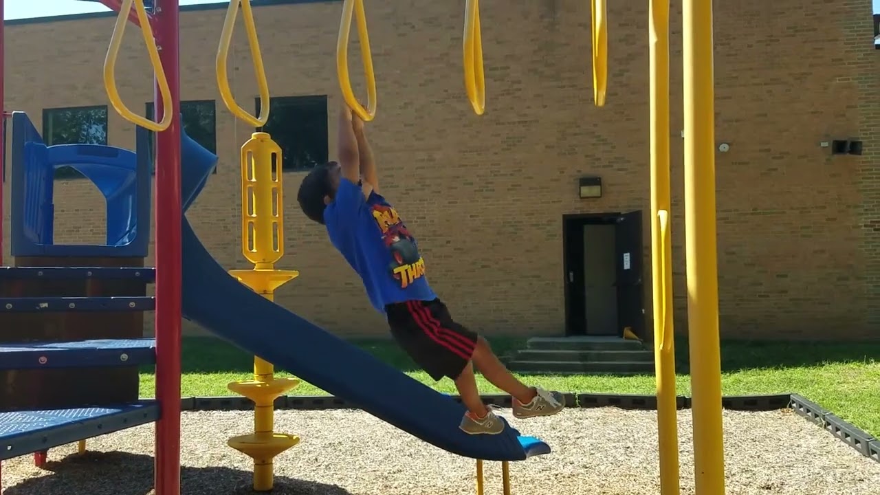 Boy gets to the end of monkey bars at playground then falls trying to land on pole platform