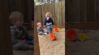 Little boy hits his brother with plastic shovel in sand box