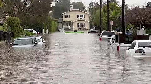 Kayaker paddles along flooded street in Santa Barb...