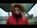 blonde woman wearing red parka coat waiting in 60mph winds