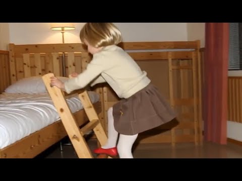 Little girl climbs the bed ladder and slips her white tights on the ladder