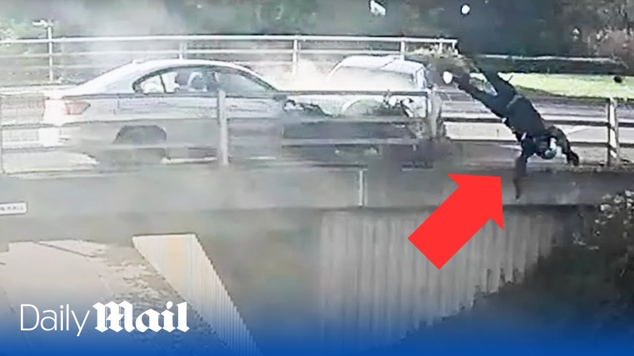 Horrifying moment biker is catapulted over the side of a bridge after being hit by road rage driver