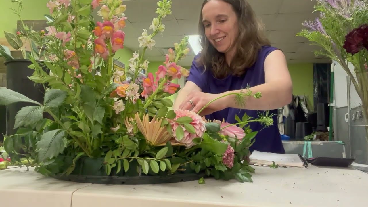 Florist designs a flower wreath to go around an urn in a feminine autumn palette
