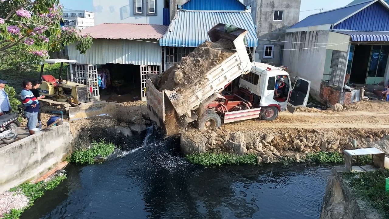 bulldozer Pouring soil into a dirty pond with Dump Truck broken garbage