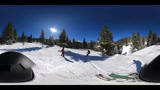 Snowboarder rides down slope then skier crashes into him as he attempts to jump hump near tree