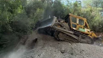 Deep in the forest, a Cat D7G excavator is descending, widening the road.