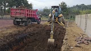 Caterpillar backhoe 420E digging and loading soil onto dump truck
