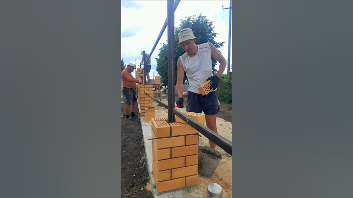 Каменщики кладут кирпичные столбы для забора. Fence construction
