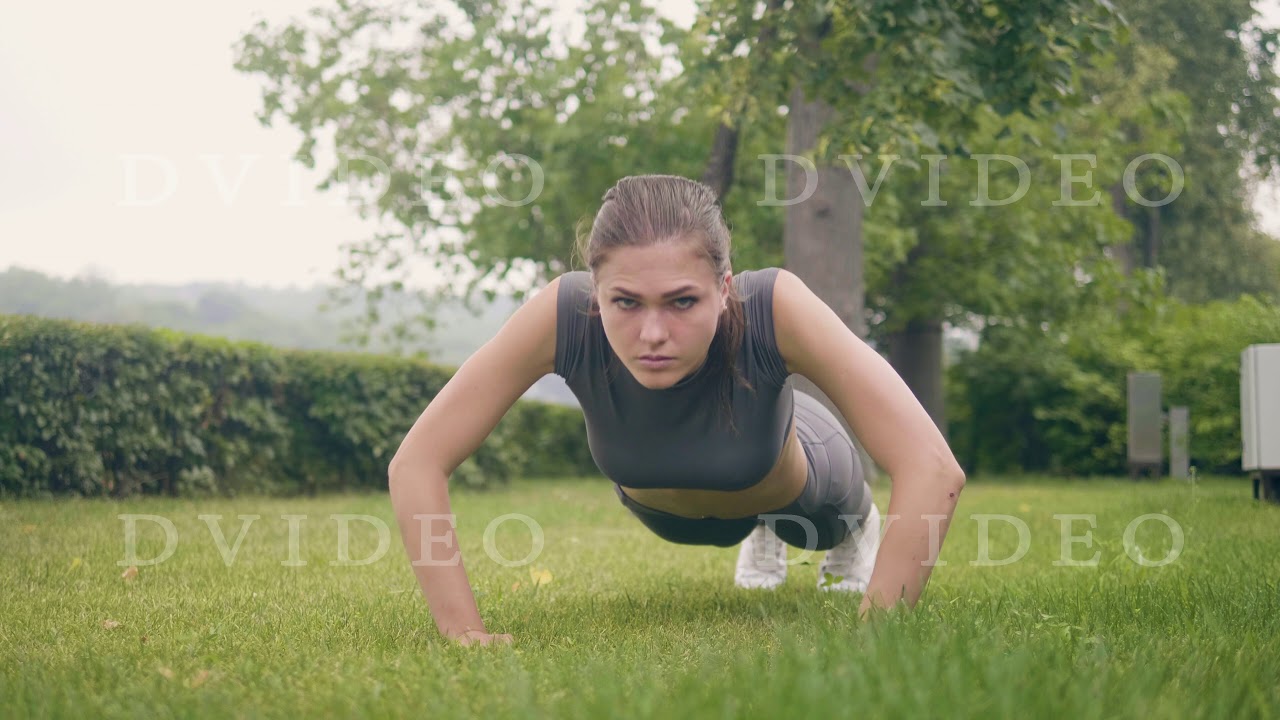 Fitness girl doing push ups exercises during outdoor training in summer ...
