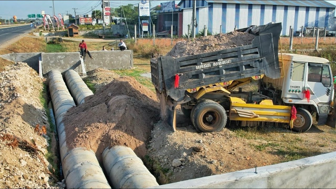 Dumping soil to bury the twin drainage next to the highway. Drivers passing by must be very careful.