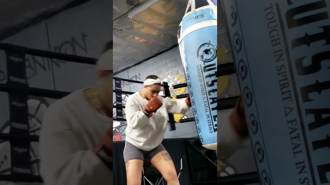 Female Boxing Coach Kam hitting the bag with Tussle hybrid gloves