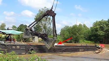 xáng cạp múc đất lể trên sông có nhiều sà lan, ghe tàu qua lại