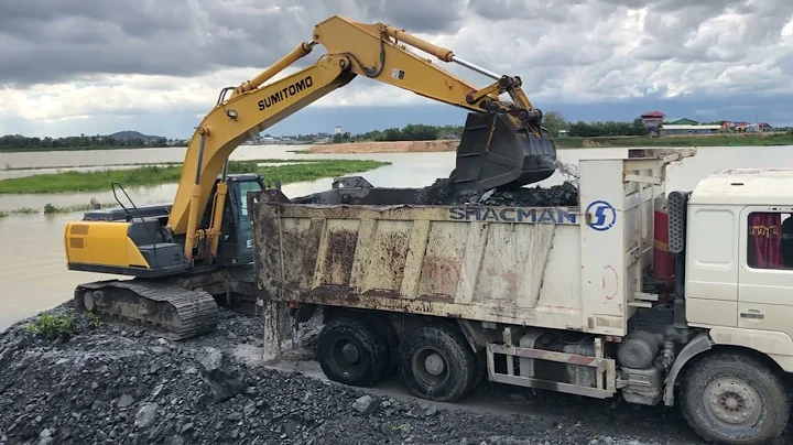 The SUMITOMO Excavator Machine Working Remove Rock Spreading From Lake To Dump truck On Construction