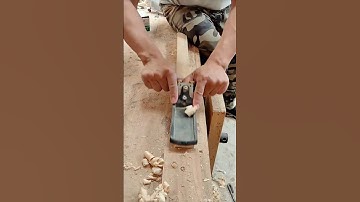 Smoothing a wooden plank with a hand planer to achieve an even surface finish