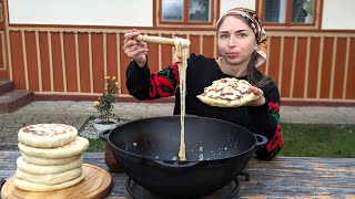 การทำอาหารหมู่บ้าน ผู้หญิงกำลังทอดขนมปังแบบดั้งเดิมที่ยอดเยี่ยมกับจานชีสจากฟาร์มบนภูเขา