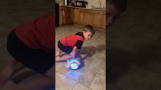 Boy riding hoverboard on his knees spins around kitchen then crashes into refrigerator and hits rear