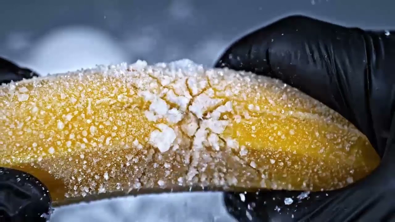 Pressing a frozen balloon filled with water — ice and burst effect mid-frame."