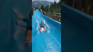 People have fun sliding down a big water slide on a mountain.