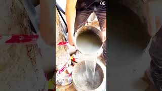 Mixing sand-cement blend with red electric stirrer in large container at dusty construction