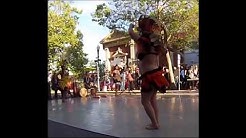 A dancer in a hula skirt dancing on the street.