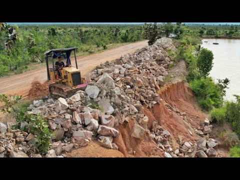 Clearing large rocks to drop down along the sidewalk of a deep pond
