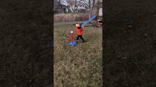 Boy hit baseball from batting tee with bat then ball hits little girl on head