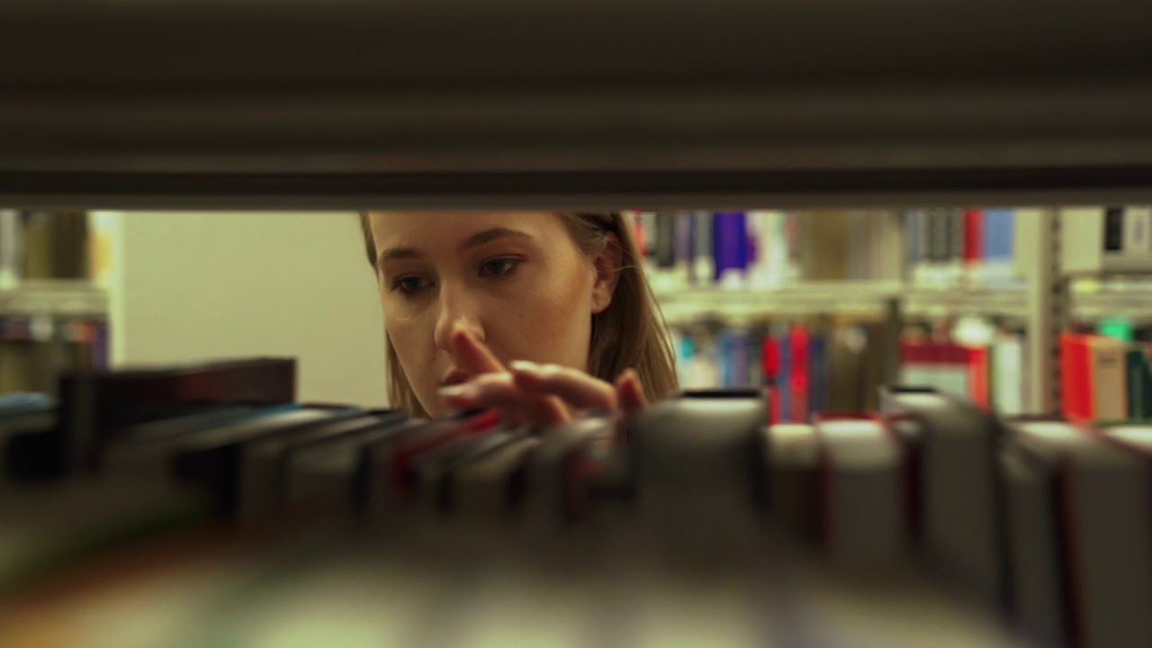 Woman Looking Through Books At Library - ULTRA HIGH Quality 4K Stock Footage