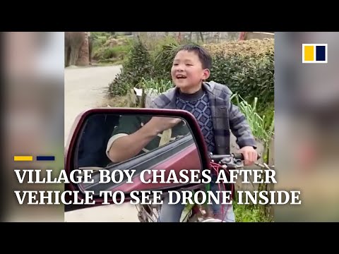 Village boy chases after a vehicle on his bike to see the drone inside