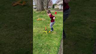 Boy wearing rain boots jumps on stomp rocket then gets hit on face in yard