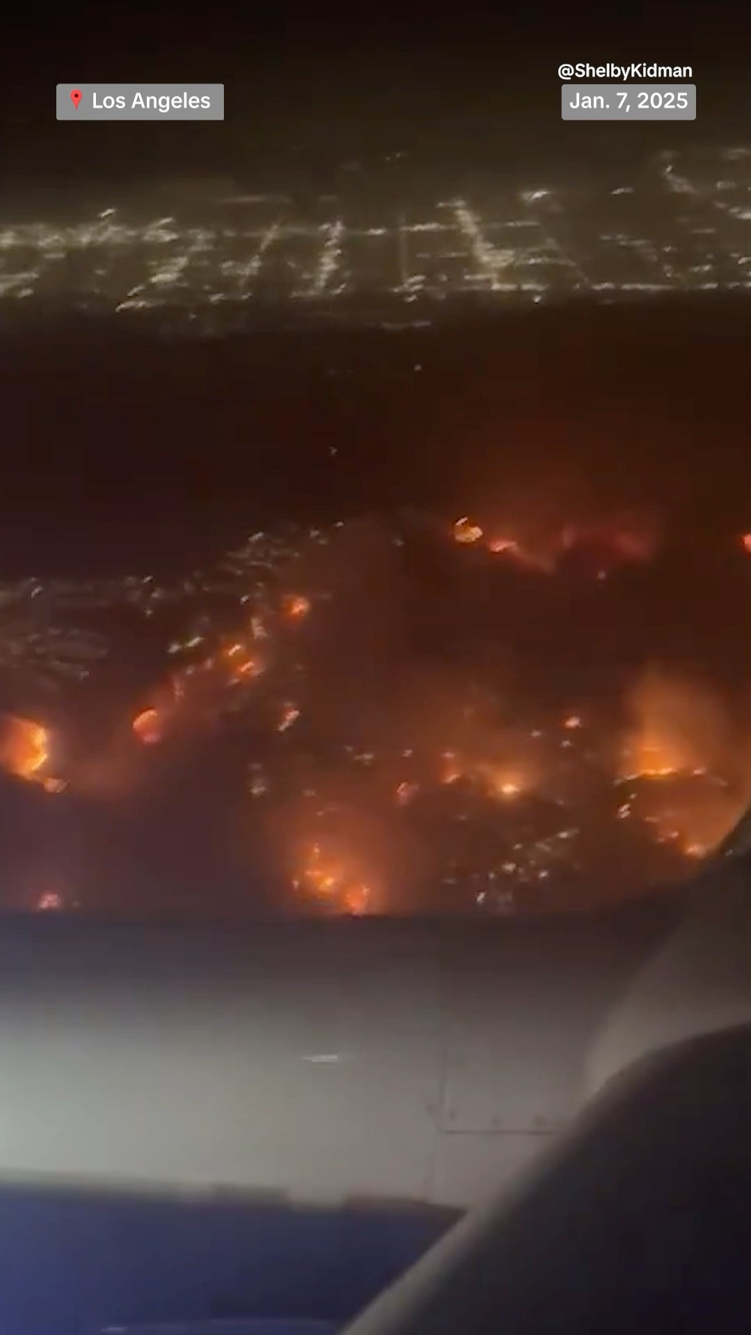 Video shot from a plane flying over Los Angeles shows the path of fast-moving wildfires.