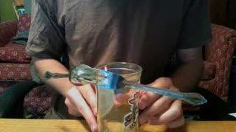 Balancing spoon and fork on edge of cup with burnt matchstick