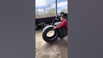 Heavy lifting: two men load massive truck tires