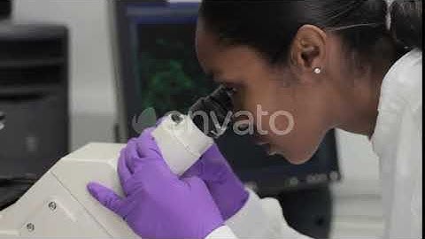Scientist looking through microscope and check results on screen | Stock Footage - Envato elements